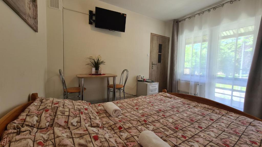 济夫努夫Dom Wypoczynkowy JOANNA的一间卧室配有一张床、一张桌子和一个窗户。