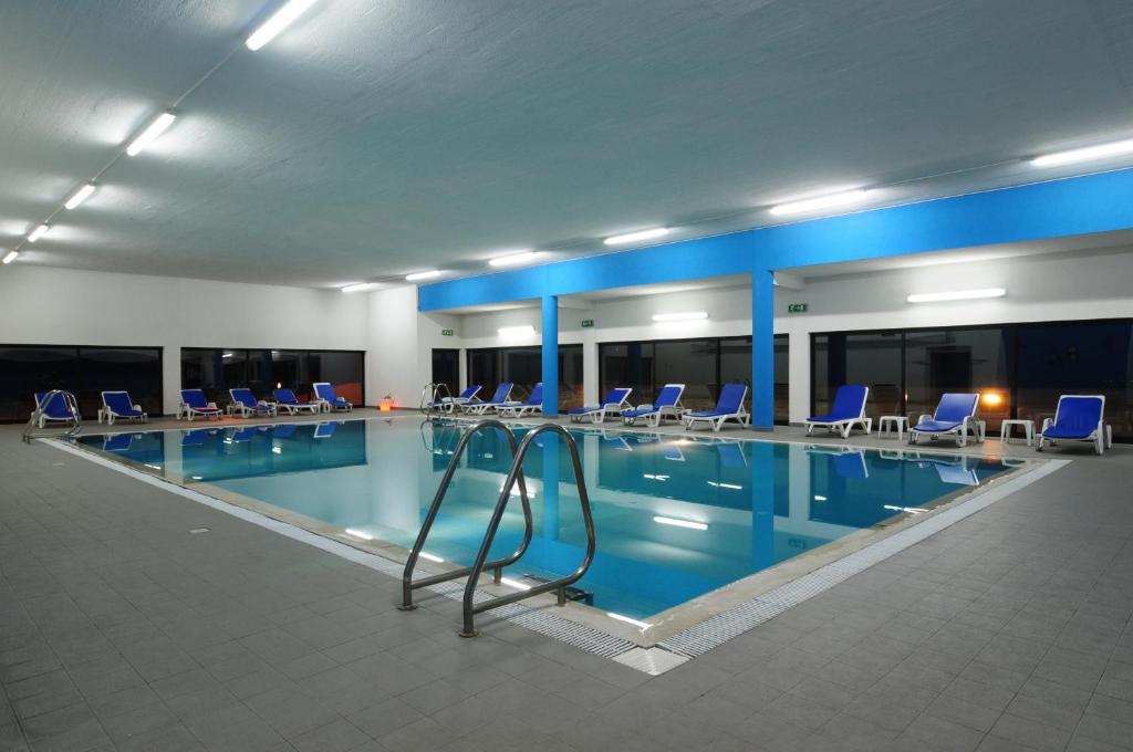 皮奥达皮奥道因娜酒店的大楼内带蓝色椅子的大型游泳池