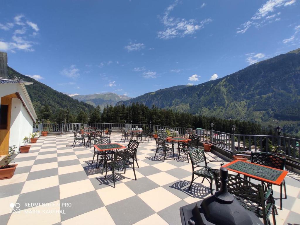 马拉里Abhilashi Residency & Spa - Centrally Heated & Air Cooled的庭院配有桌椅,背景为山脉
