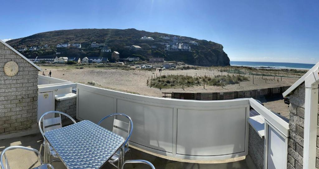 波斯陶恩Whispering Waves in Porthtowan @ Cornwall Coastal Holidays的海滩阳台的蓝色桌椅