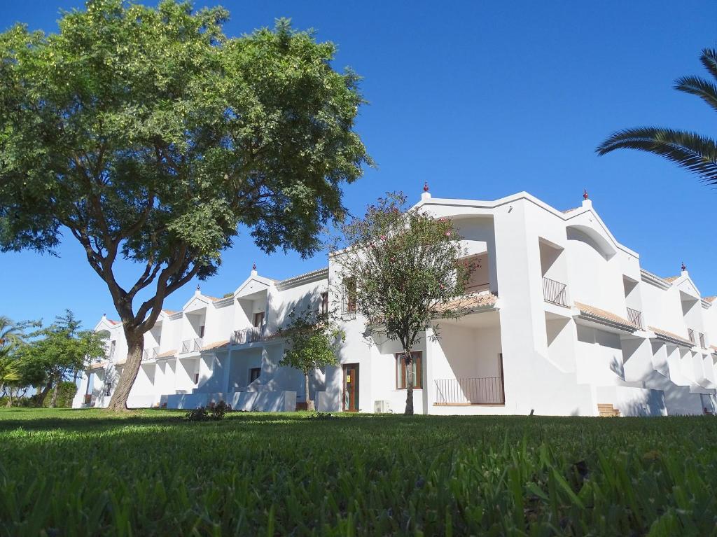 赫雷斯-德拉弗龙特拉Hotel La Parra的前面有一棵树的白色大建筑