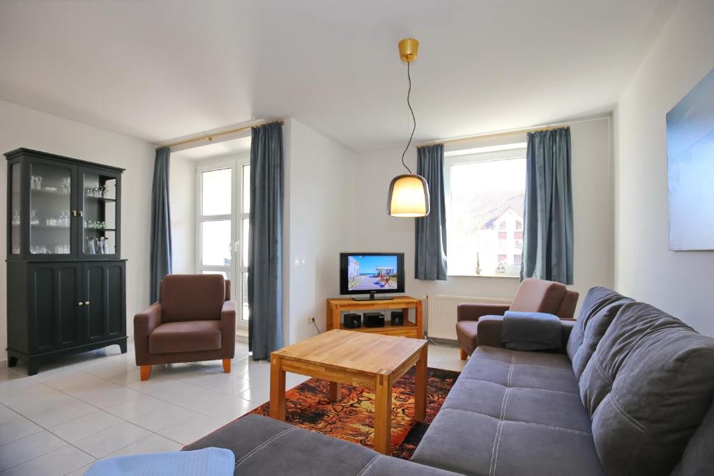 博尔滕哈根Sünnslag Wohnung 058的客厅配有沙发、椅子和电视