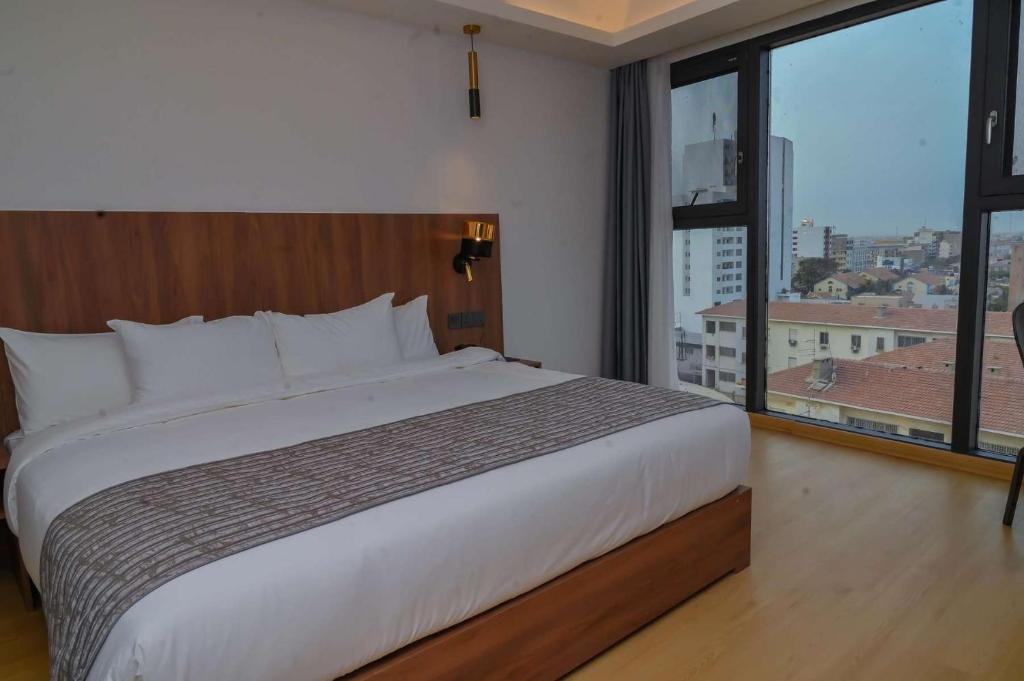 达喀尔AXIL HÔTEL的一间卧室设有一张大床和一个大窗户
