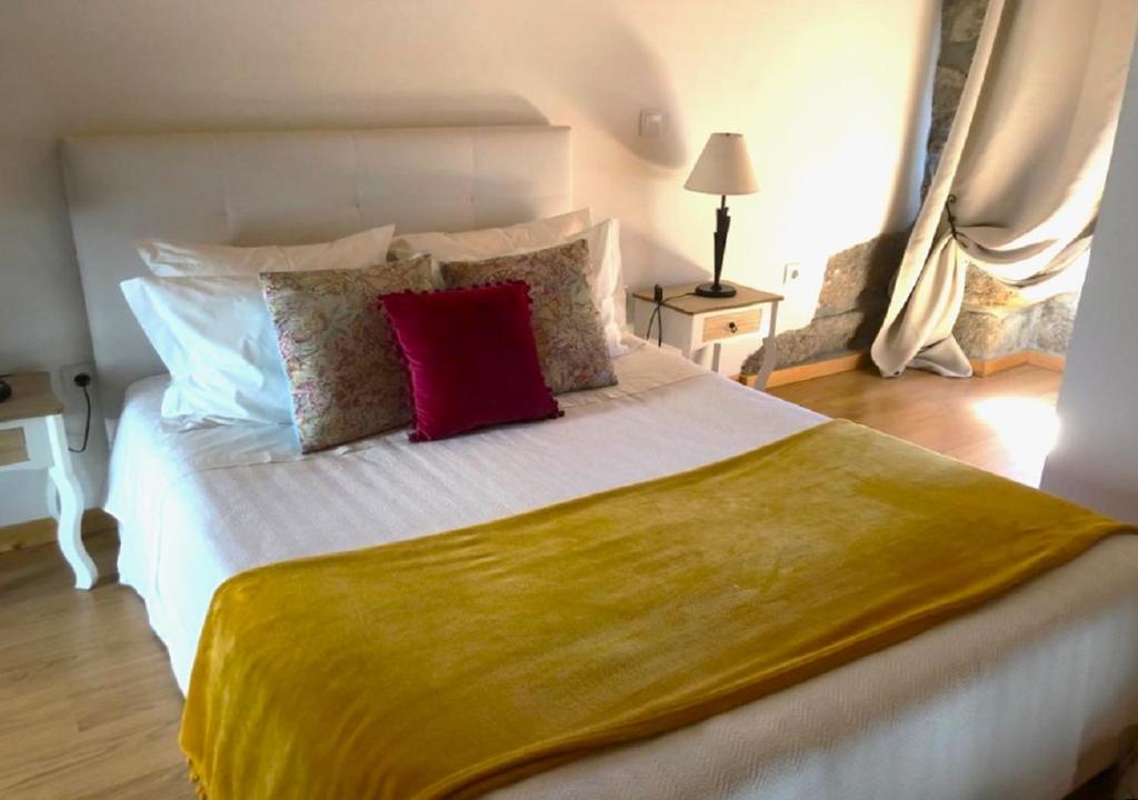 索茹Casinha da Raposeira的卧室配有带红色枕头的大型白色床
