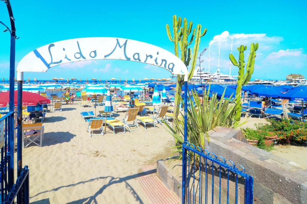 伊斯基亚温泉码头酒店的海滩上设有椅子和遮阳伞,码头上方有一片绿意盎然的海滩