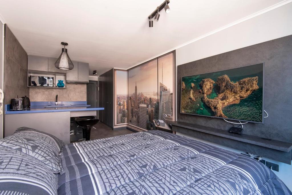 圣地亚哥Encomenderos Design Tech Comfort & Location的卧室配有一张床,墙上挂有绘画作品