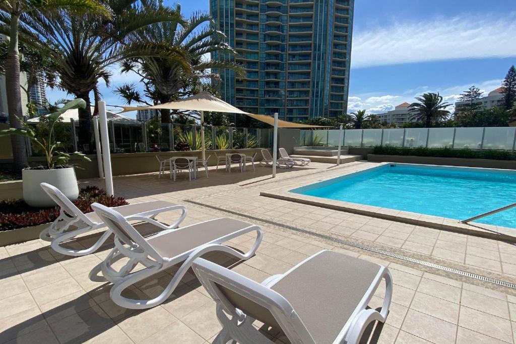 黄金海岸海冲浪海滨度假公寓酒店的一个带躺椅的游泳池和一个游泳池