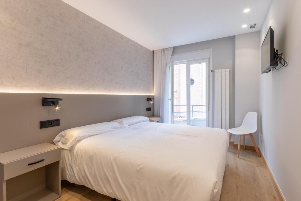 洛格罗尼奥EightRooms La Rioja Pension的卧室配有白色的床、书桌和椅子