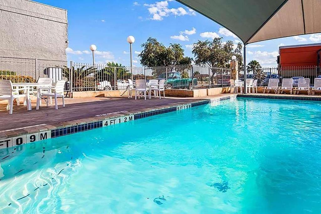 圣安东尼奥Travelodge by Wyndham San Antonio Downtown Northeast的一个带蓝色水和白色椅子的游泳池