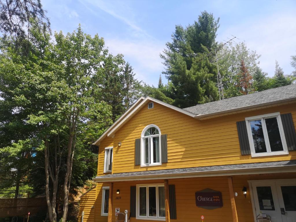瓦尔达维德Oberge Inn Val-David的一座黄色房子,后面有树木