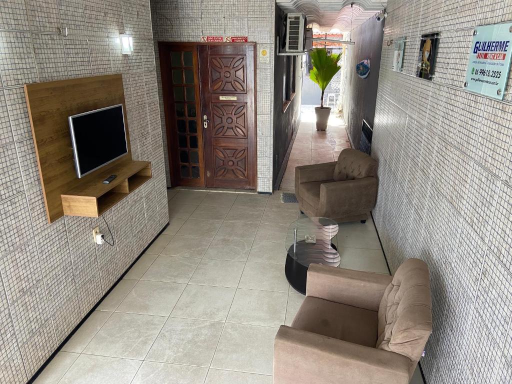 福塔莱萨Guilherme Hostel的客厅配有电视、沙发和椅子