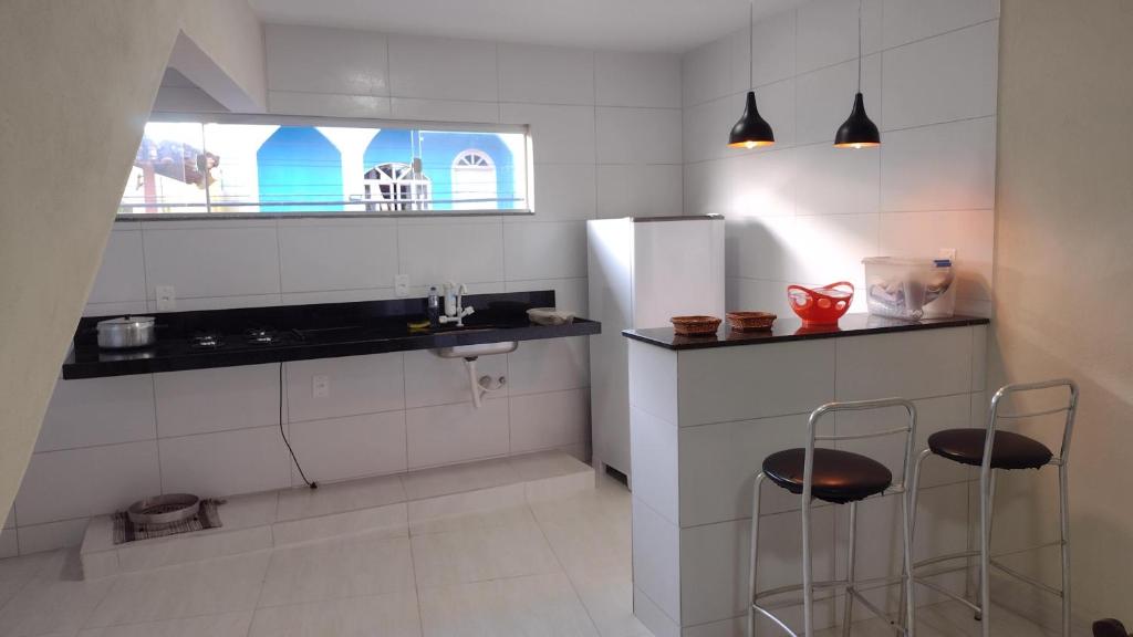 瓜拉派瑞Praia de Setiba - Kitnet的厨房配有水槽和2把凳子