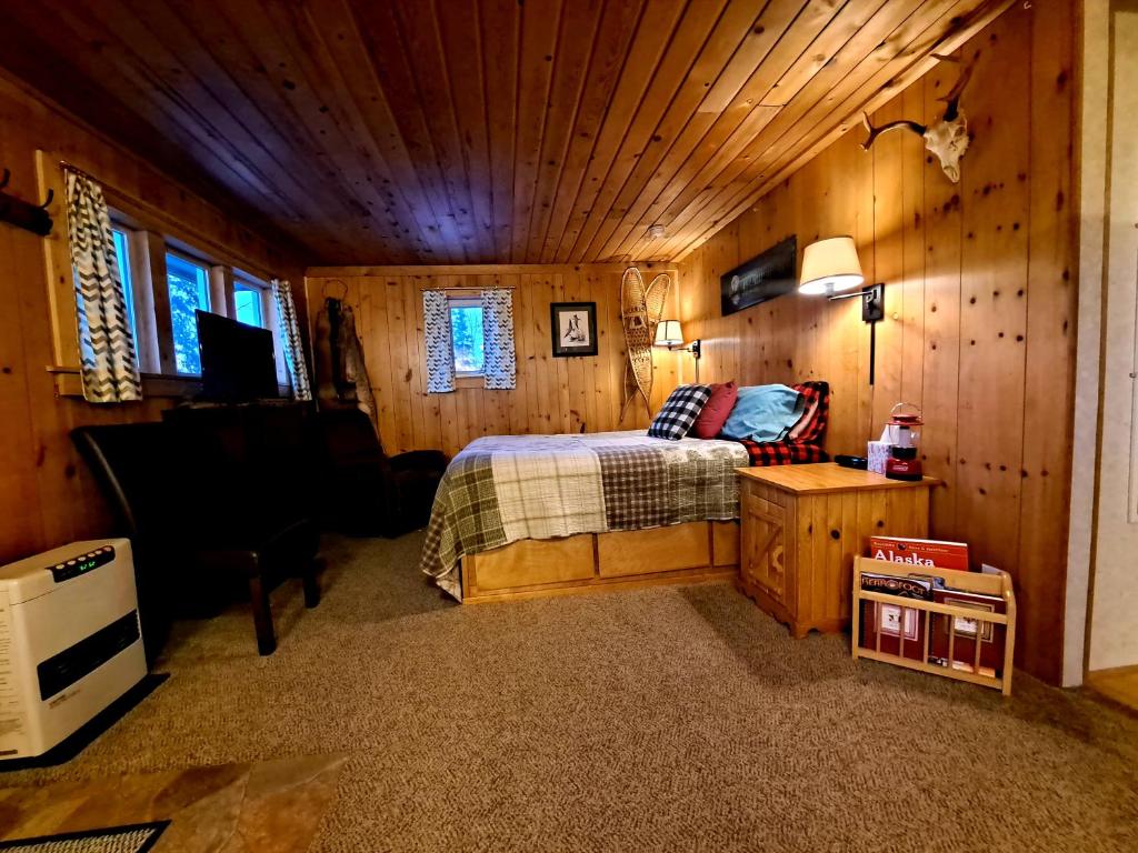 费尔班克斯Northwoods Cottage Bed and Breakfast的木制客房内的一间卧室,配有一张床