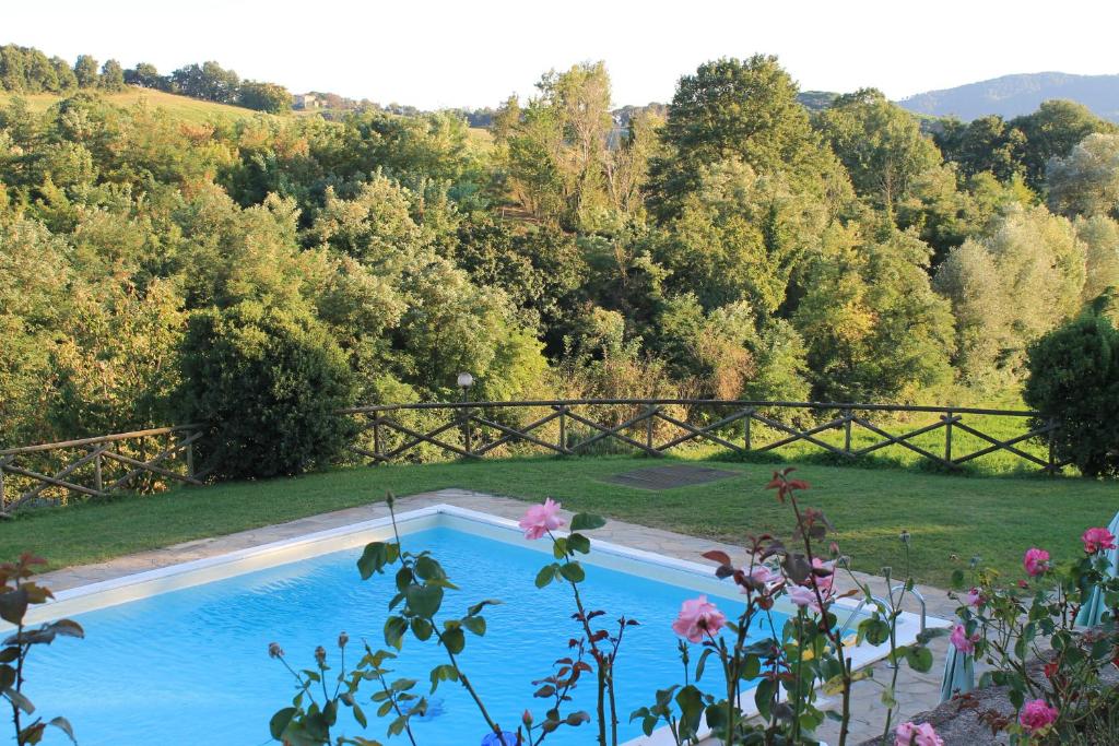 ColtavolinoFattoria di Rigone的一座种有树木和鲜花的庭院内的游泳池