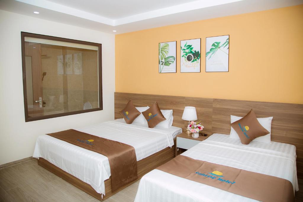 清化Sunrise Hải Tiến的两张床位于带黄色墙壁的酒店客房
