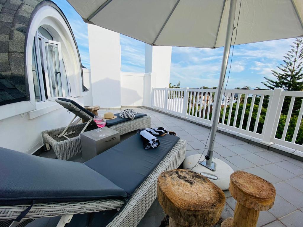 圣弗朗西斯湾Modern 3 Bedroom Townhouse in St Francis Bay的阳台的天井配有沙发和遮阳伞