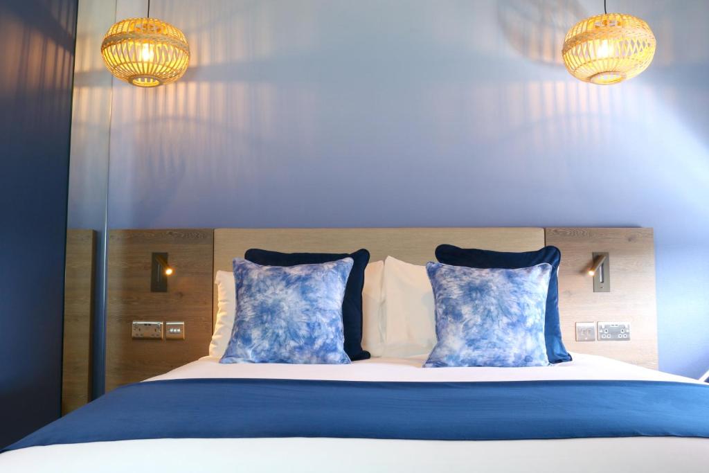唐克斯特Hex Wildlife Hotel at Yorkshire Wildlife Park的一张带蓝色和白色枕头的床和两个灯