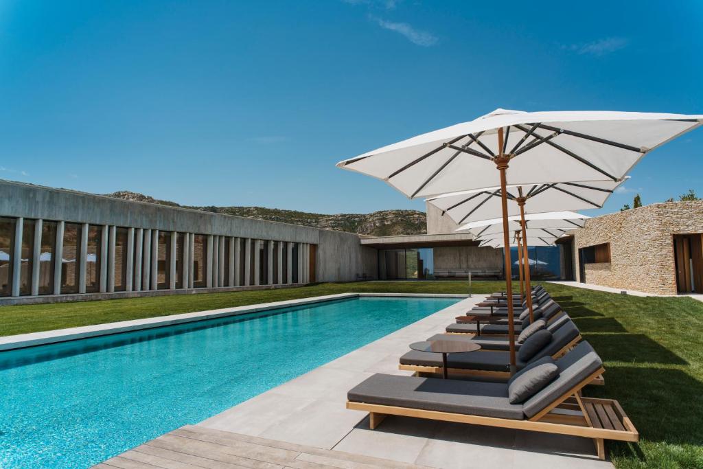 Barraca de Aguas VivasLa Galiana Golf Resort - Adults Only的游泳池旁的一组带遮阳伞的躺椅