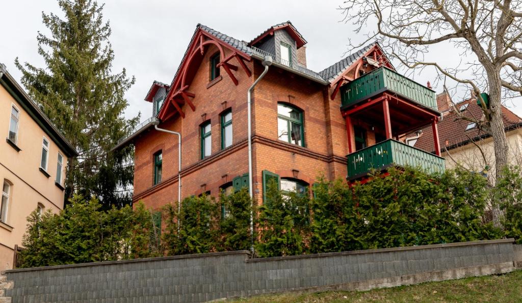 耶拿Ferienwohnung Jenzigblick的大型红砖房屋 - 带绿色阳台