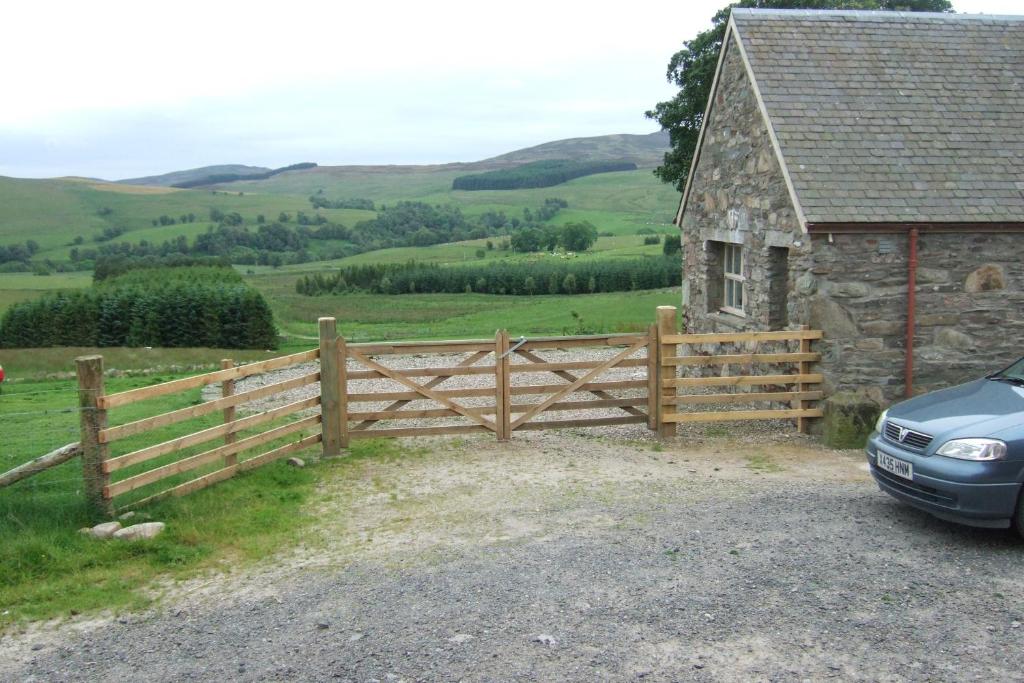 邓凯尔德Tomnagairn Cottage的谷仓和汽车旁的木栅栏