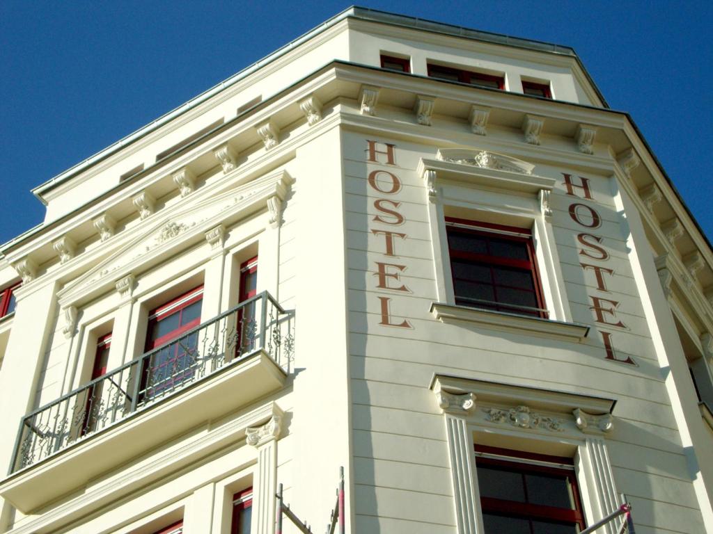 莱比锡Sleepy Lion Hostel & Apartments Leipzig的白色的建筑,上面有酒店标志