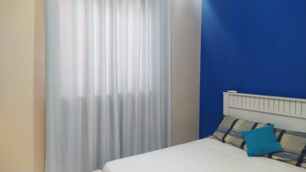 卡皮托利乌Cantinho Xodó的一间卧室配有一张带蓝白色窗帘的床