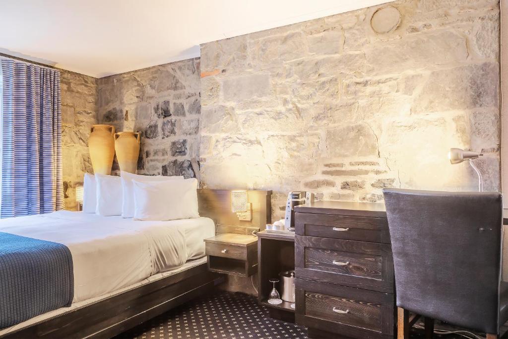 魁北克市逸轩综合酒店的一间卧室设有一张床和石墙