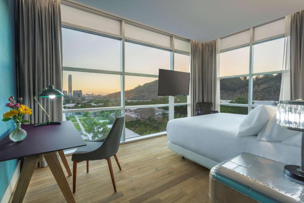 圣地亚哥NH Collection Santiago Casacostanera的酒店客房设有一张床、一张书桌和窗户。