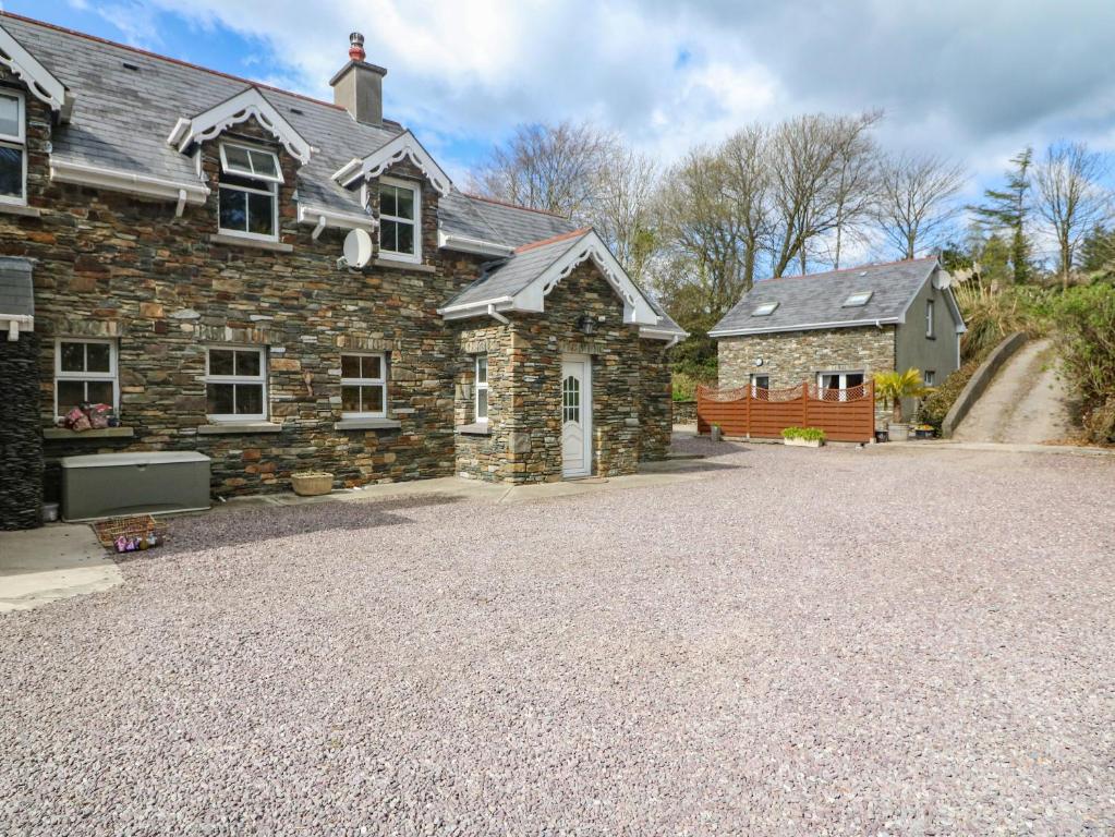 SkahanaghLis-Ardagh Cottage 1的前面有车道的石头房子