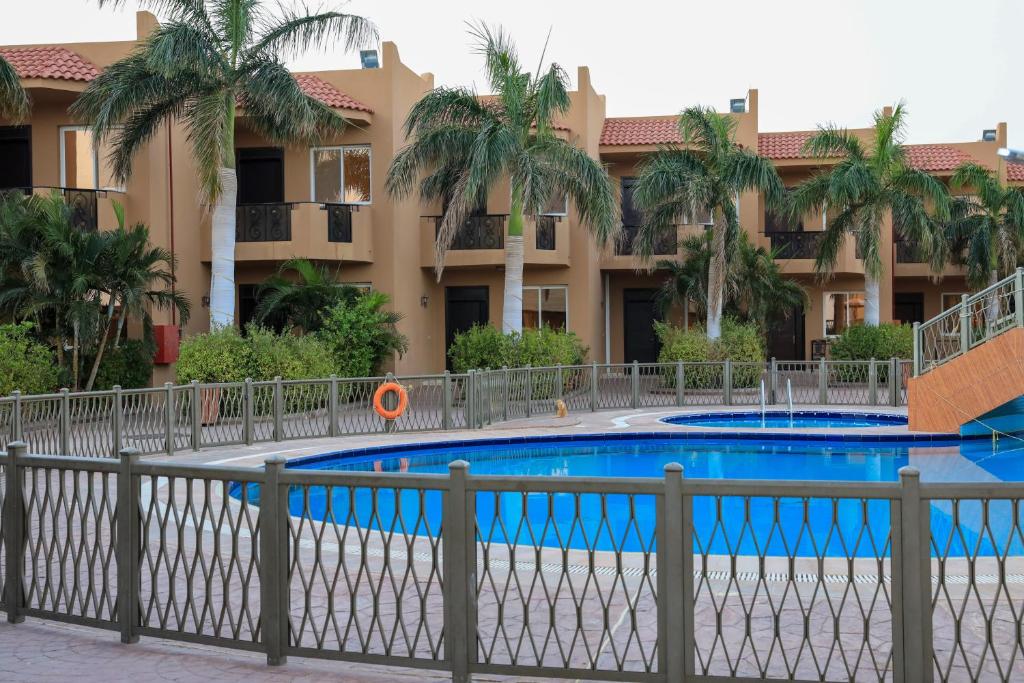 延布Alahlam Resort Yanbu的棕榈树建筑前的游泳池