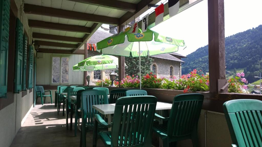 Troistorrents海尔维提亚住宿加早餐旅馆的一间设有绿色桌椅和遮阳伞的餐厅