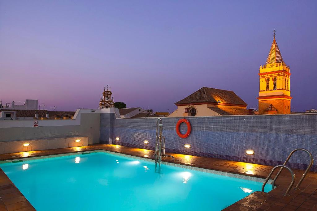 塞维利亚圣吉尔酒店的一座带钟楼建筑屋顶上的游泳池