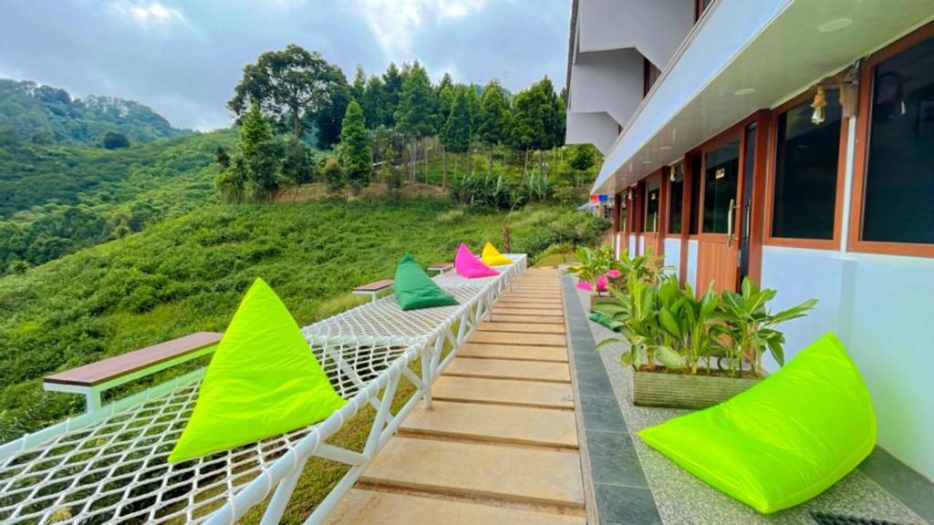 CampakaDe Pointé Resort & Resto的阳台配有绿色和粉红色的椅子,享有山景