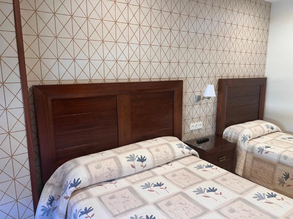 贝纳文特Hostal Avenida的一间卧室设有两张床和瓷砖墙