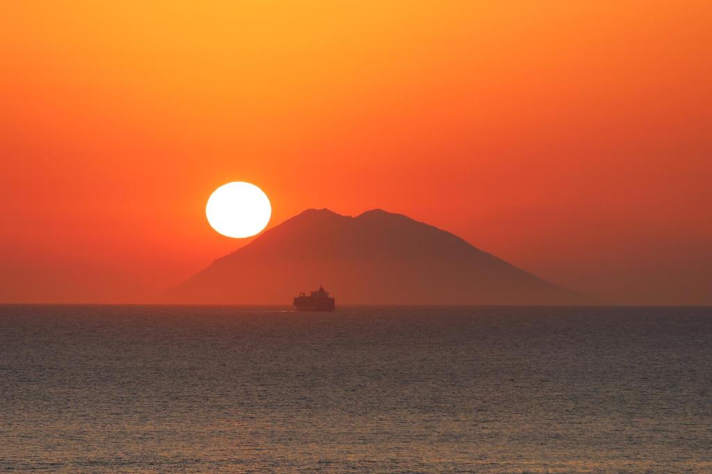 特罗佩阿Deus Accomodation的日落时分在海洋中与山一起航行的船只