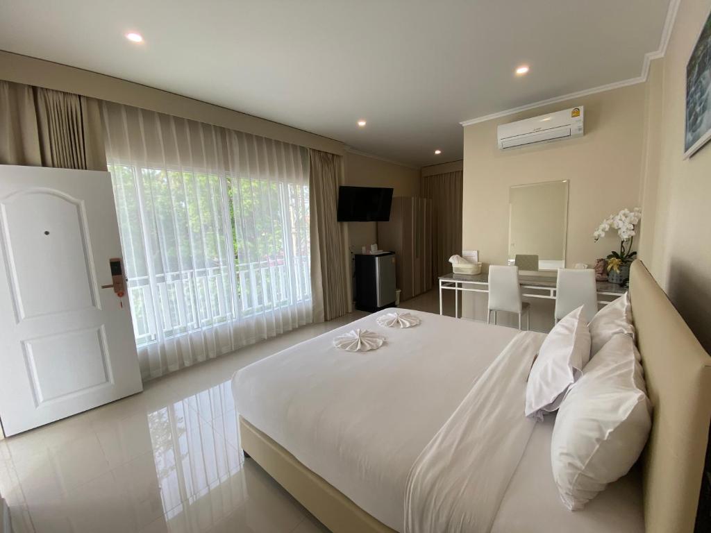 四色菊Siri Ville Hotel的卧室配有一张白色的大床和一张桌子