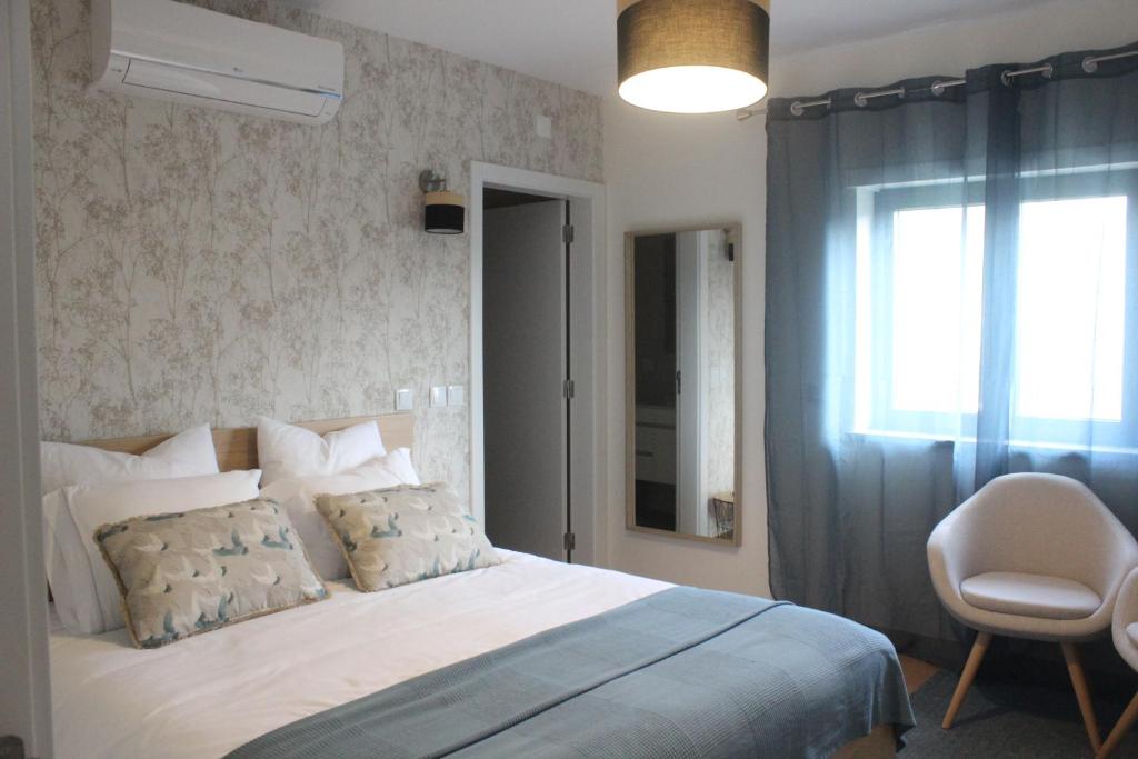 阿加尼尔Casa Dona Alzira的一间卧室设有一张床、一个窗口和一把椅子