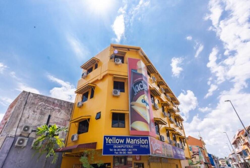 马六甲Yellow Mansion Hotel的黄色的建筑,前面有标志