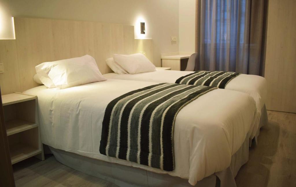 圣地亚哥－德孔波斯特拉Santa Filomena的卧室配有一张带白色床单和枕头的大床。