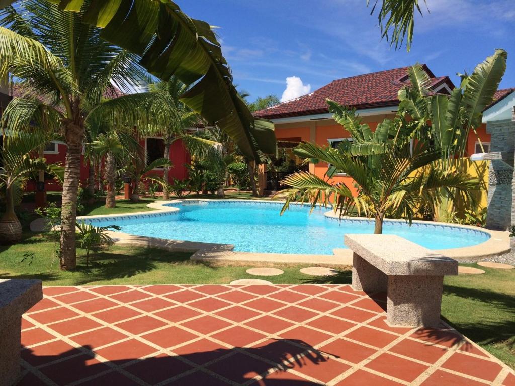 邦劳阿罗那珊瑚花园度假村服务式公寓的房屋旁带长凳的游泳池