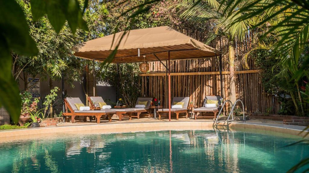 阿鲁沙Villa Arumeru的一个带桌椅和遮阳伞的游泳池