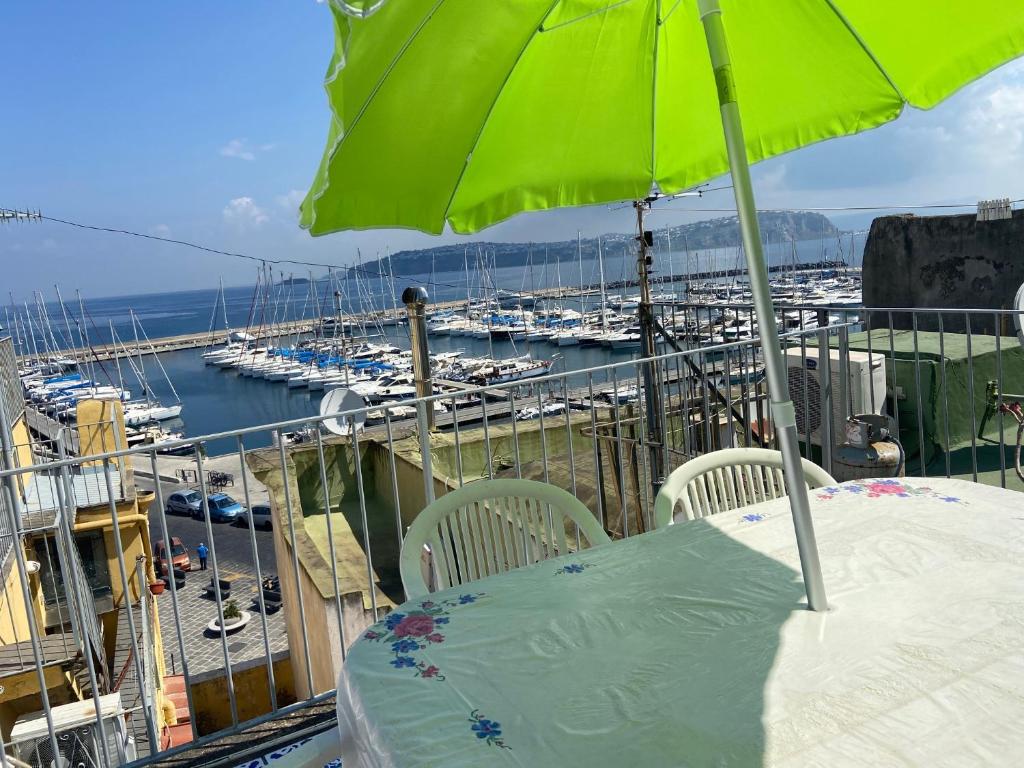 普罗奇达Procida Marina Grande的阳台上配有绿伞和小船的桌子