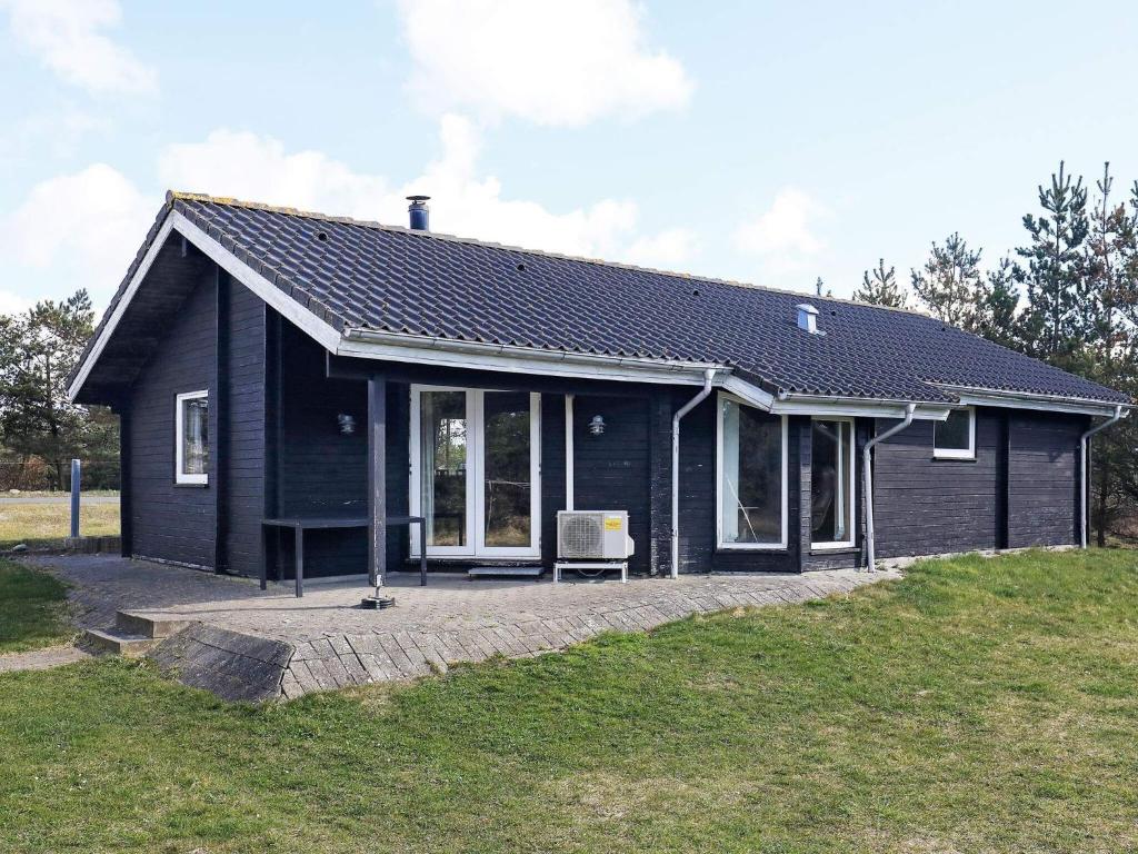 SindrupHoliday Home Fjordternevej的前面有长凳的黑房子