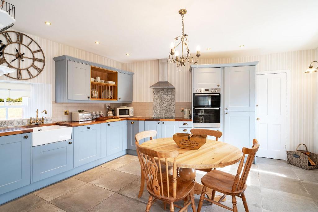 基里缪尔Thrums Cottage的厨房配有蓝色橱柜和木桌