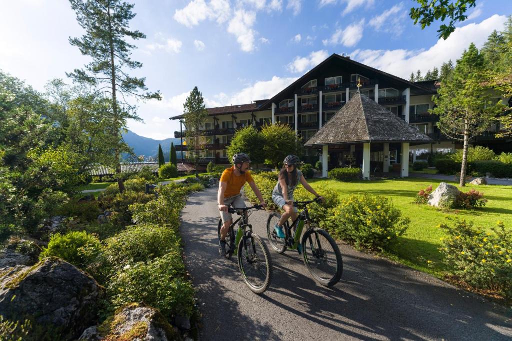 格赖瑙艾比塞酒店的两个人骑着自行车沿着房子前面的小径骑着