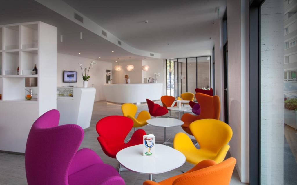 卢加诺卢加诺城市酒店的配有桌子和五颜六色椅子的房间