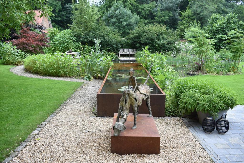 Merkem梅尔肯帕斯托雷住宿加早餐酒店的坐在花园长凳上的雕像