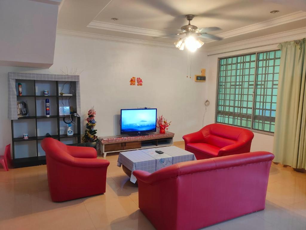 诗巫NH Homestay Sibu的客厅配有2把红色椅子和电视