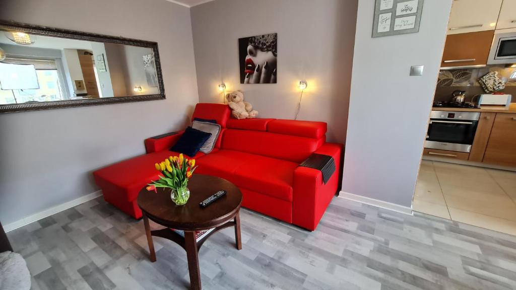 索波特Apartament z widokiem na las的客厅里一张红色的长沙发,上面有泰迪熊