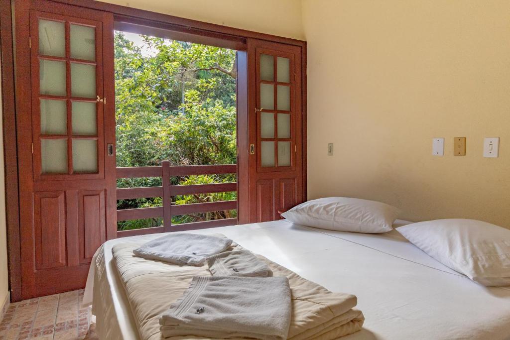 特林达德Pousada do Marquinhos的一间卧室设有两张床,窗户设有门